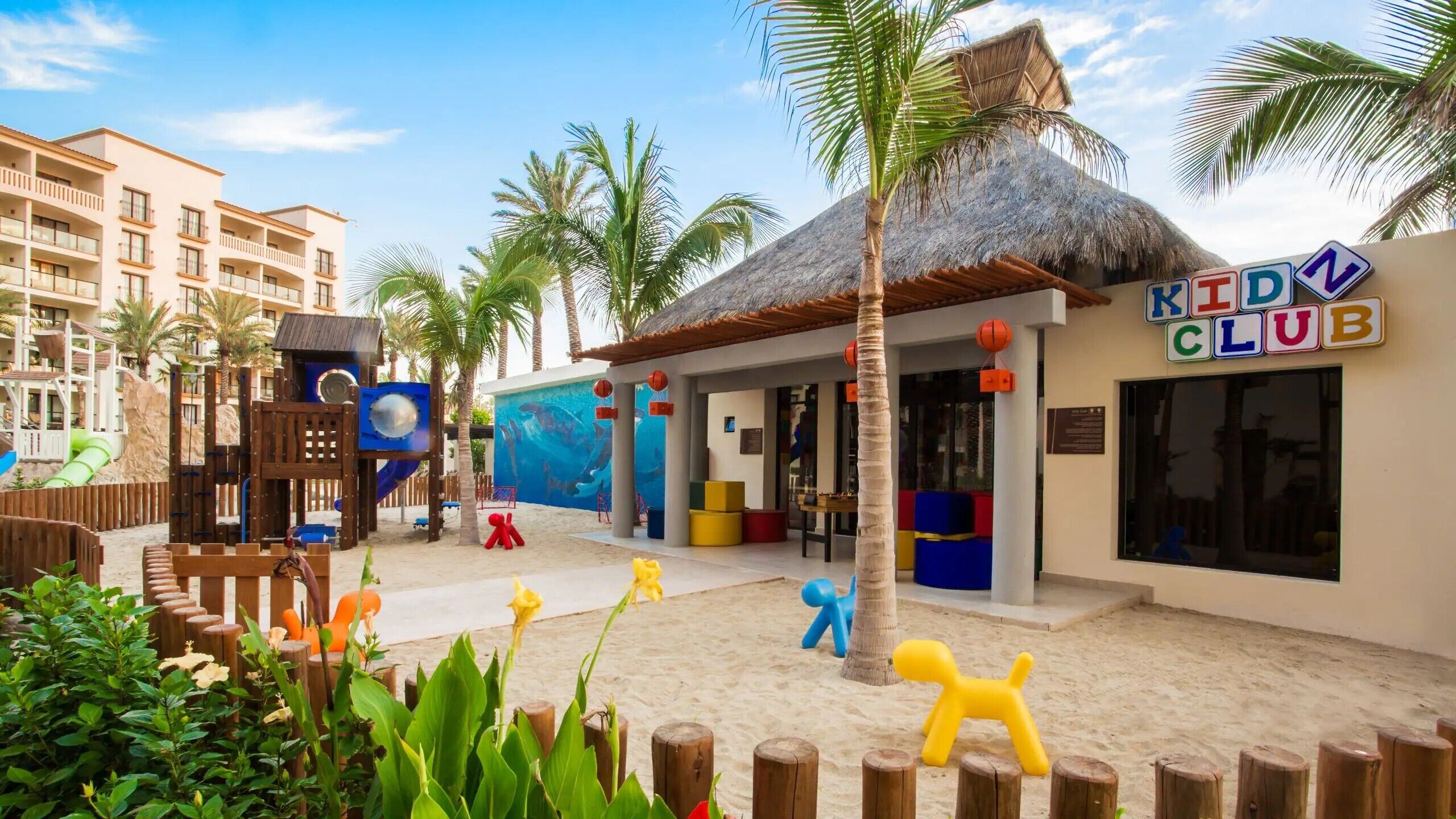 A children's play area with a pool, palm trees, and a building labeled 'KIDD CLUB'.