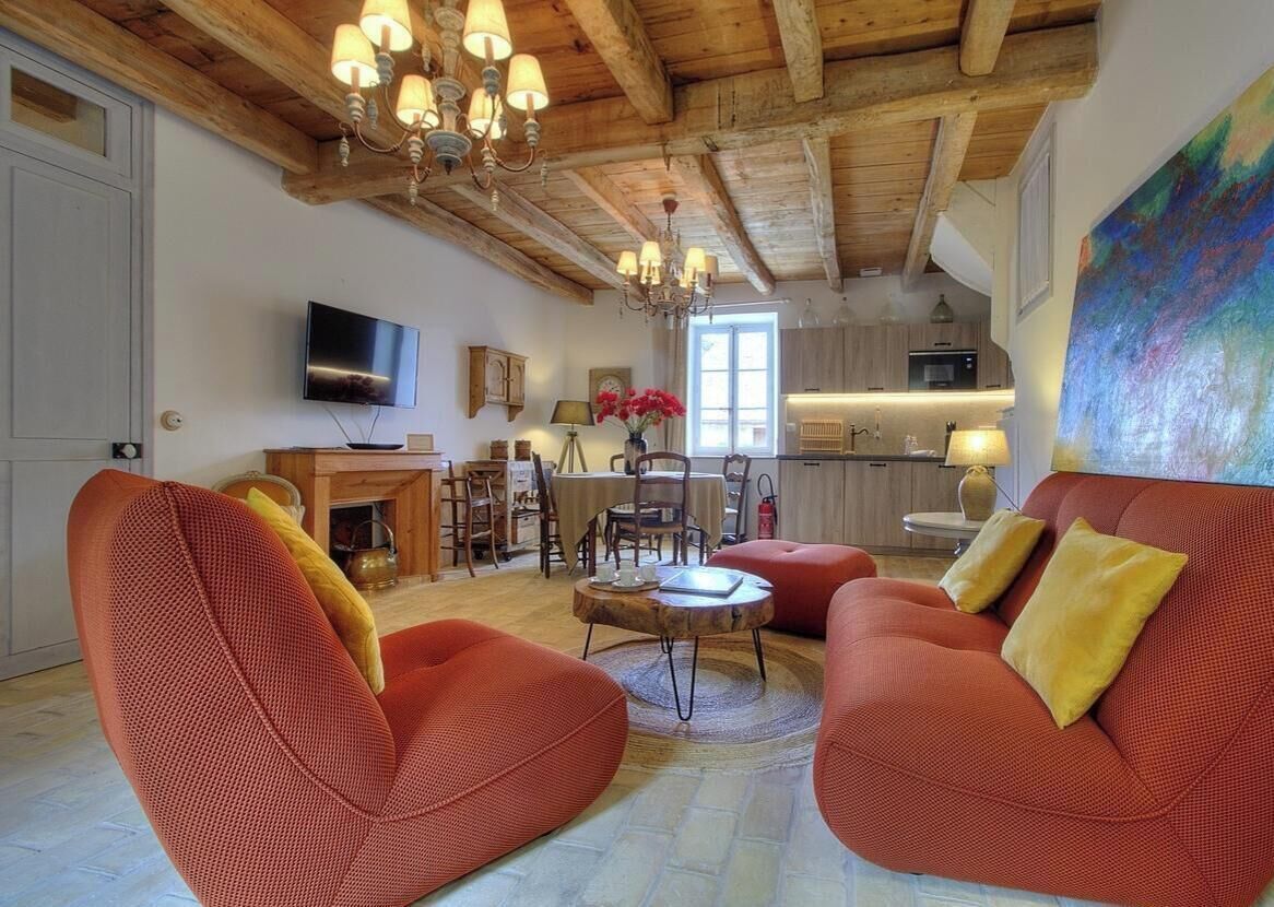 A living room with red sofas, a television, and a chandelier.