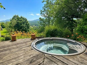 Een hottub op een houten terras met een prachtig uitzicht op bergen en bomen.