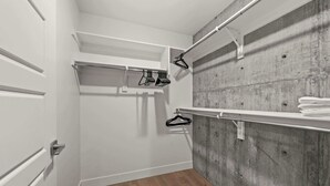 A walk-in closet with a wooden floor, white doors, and a concrete wall. - Lux SLC - Pool - Gym - Rooftop (Salt Lake City)