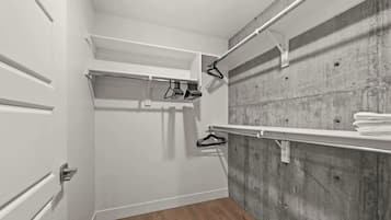 A walk-in closet with a wooden floor, white doors, and a concrete wall.