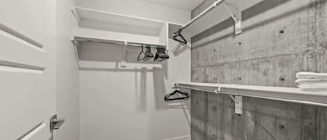 A walk-in closet with a wooden floor, white doors, and a concrete wall.
