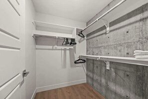 Ein begehbarer Kleiderschrank mit Holzboden, weißen Türen und einer Betonwand.