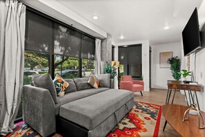 A modern living room with a grey sofa, a pink chair, and a wooden side table.