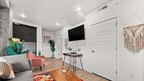 A modern living room with a sofa, coffee table, and a TV mounted on the wall. - Lux SLC - Pool - Gym - Rooftop (Salt Lake City)