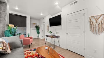 A modern living room with a sofa, coffee table, and a TV mounted on the wall.