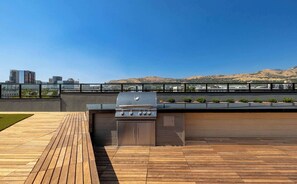 Ein Außenbereich mit Grill, Holzdeck und Blick auf Stadt und Hügel.