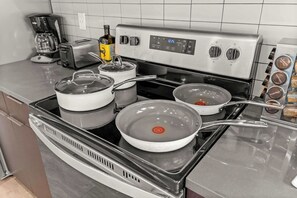 A kitchen with a stove, pots, a coffee maker, and a bottle of olive oil. - Lux SLC - Pool - Gym - Rooftop (Salt Lake City)