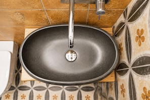 A bathroom with a black sink, a chrome faucet, and patterned tiles on the wall. - Caramanna Studio (Bologna)