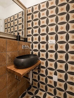A bathroom with a round sink, a mirror, and patterned tiles. - Caramanna Studio Apartment (Bologna)