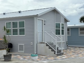 Ein zweistöckiges Haus mit Veranda, Treppe und einem kleinen Garten.