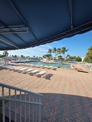 A pool area with lounge chairs and a covered section. - Immaculate waterfront home on Nettles Island Jensen Beach FL,  Beach Access (Jensen Beach)