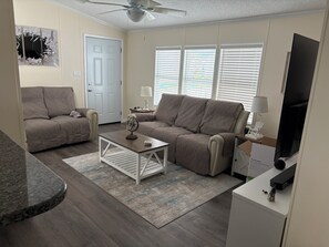 Ein Wohnzimmer mit zwei Sofas, einem Couchtisch, einem Fernseher und einem Deckenventilator.