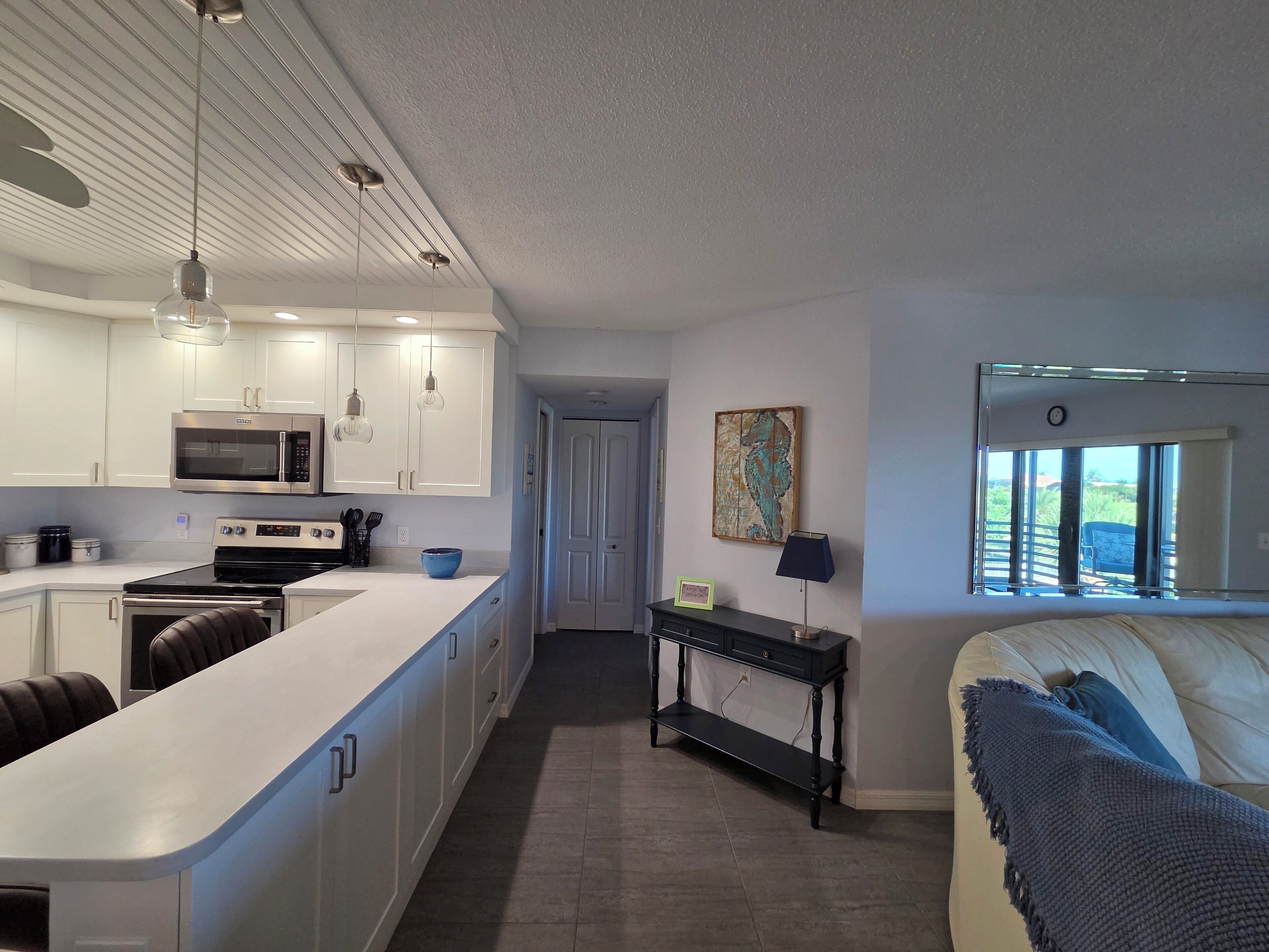 A modern kitchen with white cabinetry, a built-in microwave, and a central island.