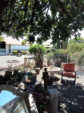 Un jardin agrémenté de diverses plantes, d’une statue et de mobilier d’extérieur.