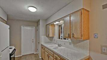 A kitchen with a double sink, wooden cabinets, and a white countertop.