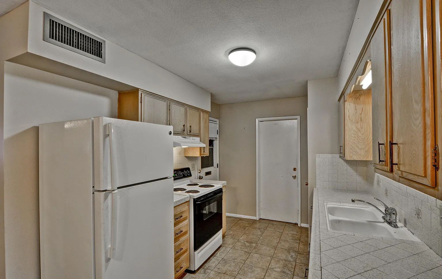 A compact kitchen with a refrigerator, stove, oven, and sink.