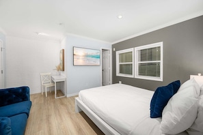 Een slaapkamer met een bed, een bureau en een stoel.