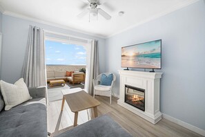 A living room with a fireplace, a television, and a view of the beach. - West Oceanfront Oasis 2-3-4-6-7 (Newport Beach)