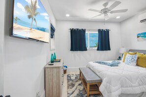 Ein Schlafzimmer mit einem Bett, einer Sitzbank, einem Schreibtisch, einem Fernseher und einem Deckenventilator.