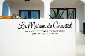 A white reception desk with the text 'La Maison de Chantal' and contact information for Tower 17 Properties. - West Oceanfront Oasis 3-4-5-6-9 (Newport Beach)