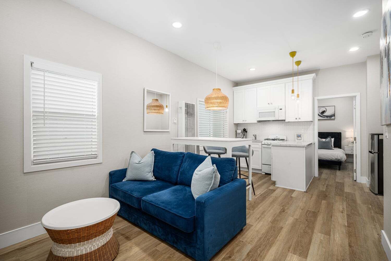 Een moderne woonkamer met een blauwe bank, een keuken met witte kasten, en een eethoek.
