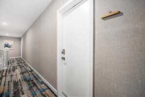 A hallway with a patterned carpet, a white door, and a small wooden shelf on the wall. - West Oceanfront Oasis 3-4-5-6-9 (Newport Beach)