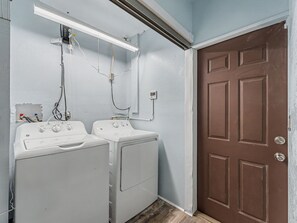 A laundry room with two front-loading washing machines, a wall-mounted heater, and a brown door. - Waterfront Retreat: Swim Spa, Dock, Kayaks, Paddleboards & Gulf Access (Hudson)