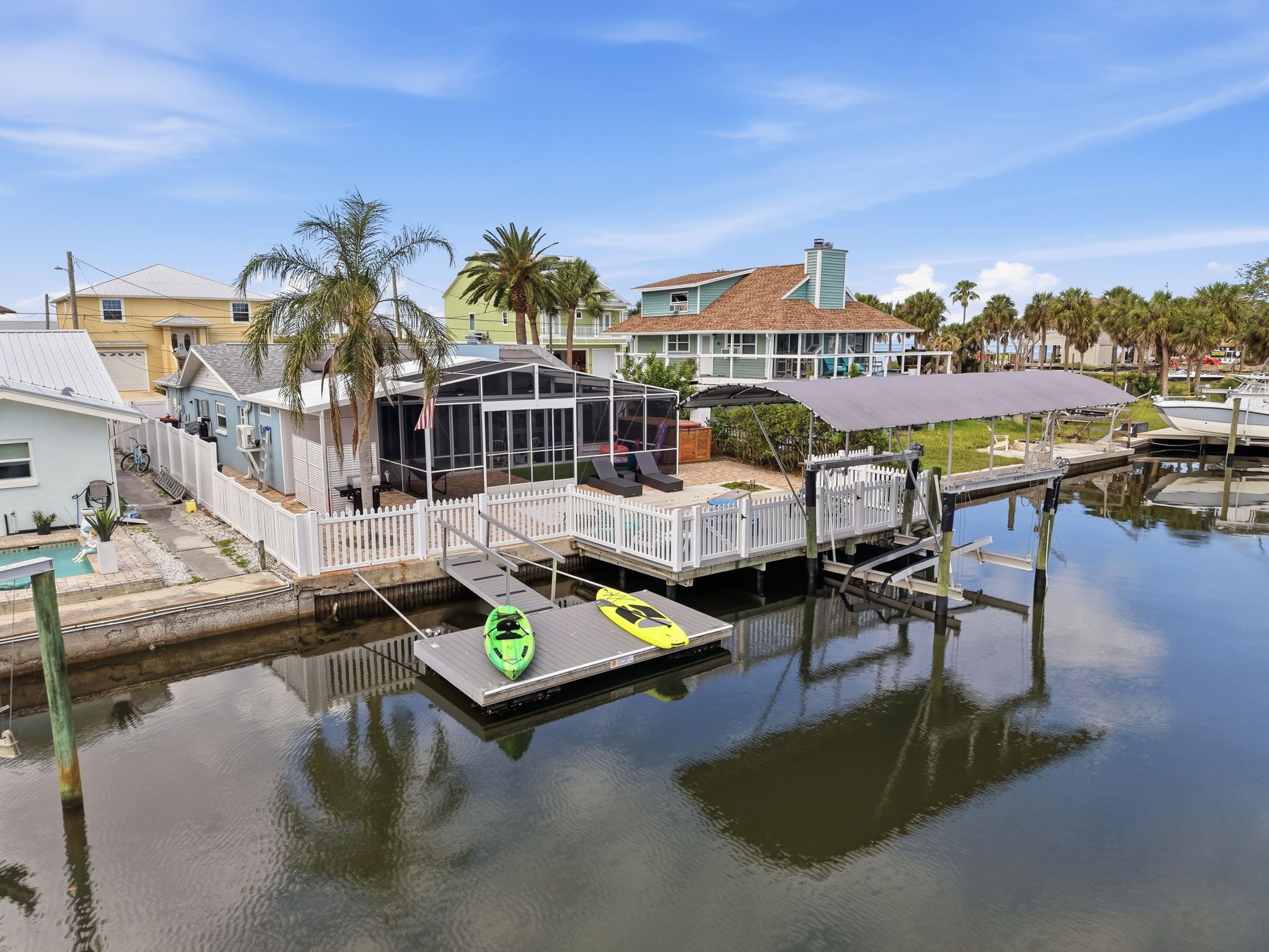 A waterfront property with a dock, a covered outdoor seating area, and a pool.