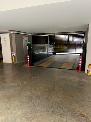 A parking garage entrance with a control panel, a fire extinguisher, and a striped safety mat. - A Sober and Elegant Loft Apartment in Chapinero (Bogotá)