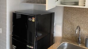 A compact kitchen with a black refrigerator, a granite countertop, a stainless steel sink, and white cabinets. - A Sober and Elegant Loft Apartment in Chapinero (Bogotá)