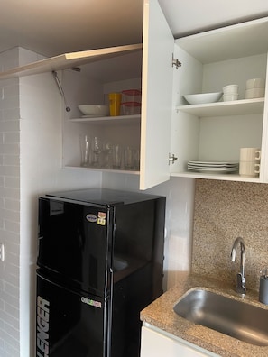 A compact kitchen with a black refrigerator, a granite countertop, a stainless steel sink, and white cabinets. - A Sober and Elegant Loft Apartment in Chapinero (Bogotá)