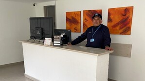 A reception desk with a flat-screen monitor, a cash register, and a sign indicating a service charge. - A Sober and Elegant Loft Apartment in Chapinero (Bogotá)