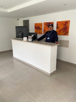 A reception desk with a flat-screen monitor, a cash register, and a sign indicating a service charge. - A Sober and Elegant Loft Apartment in Chapinero (Bogotá)
