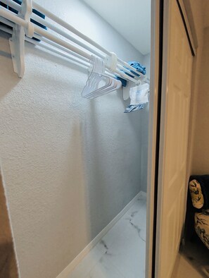 A bathroom with a towel rack holding several towels and a shower curtain rod. - Blue Water Palms • Heated Pool • Beaches & River (Palm Bay)
