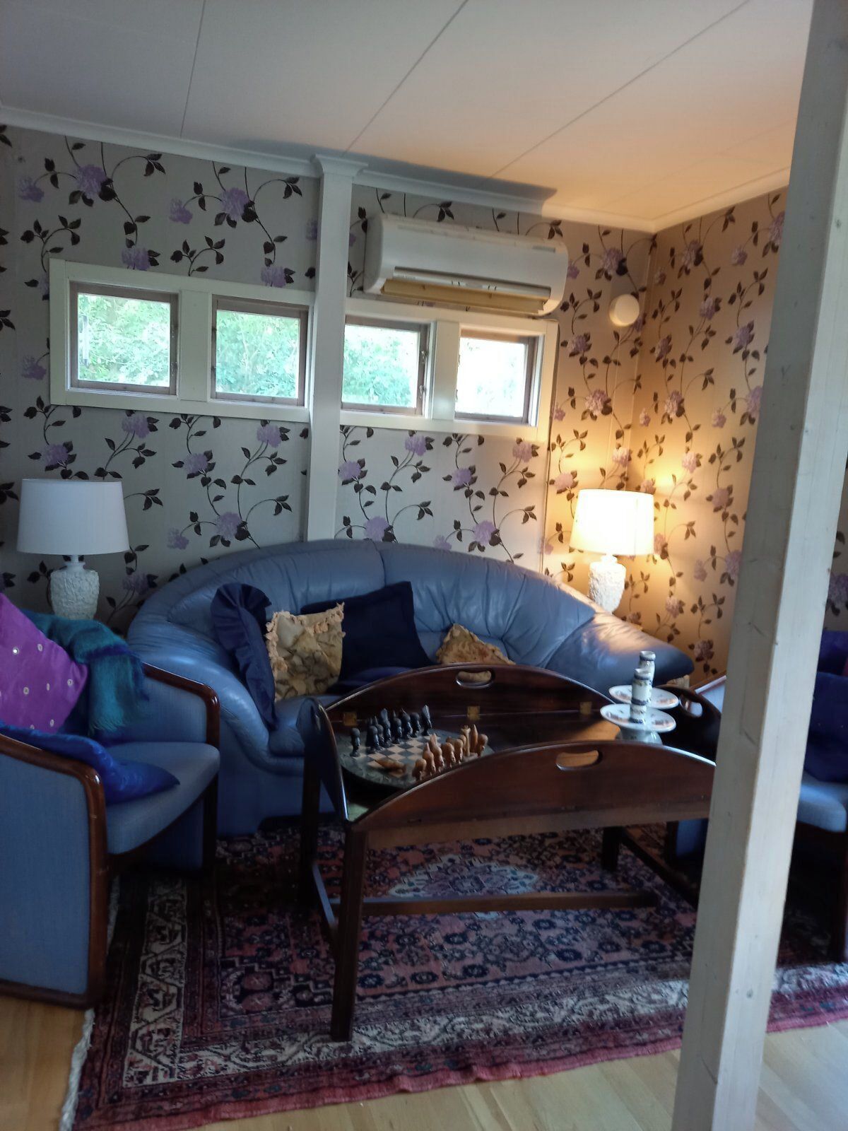 Una sala acogedora con un sofá azul, una mesa de ajedrez y un tapete estampado.