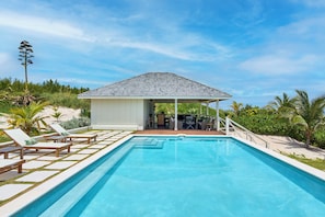 A swimming pool with lounge chairs and a covered patio area. - Bohemia Bunkhouse - Steps to Pink Sand, Heated Pool (Governor's Harbour)