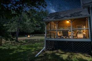 A cabin with a deck, a fire pit, and a starry night sky. - Northern Escape | Sauna, Dock & Lake Access (Butternut)