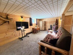 A wooden cabin interior with a television, a sofa, a table, and a fireplace. - Northern Escape | Sauna, Dock & Lake Access (Butternut)