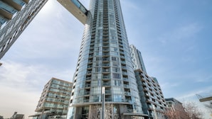 Un edificio moderno alto y cilíndrico con varios balcones y grandes ventanales.