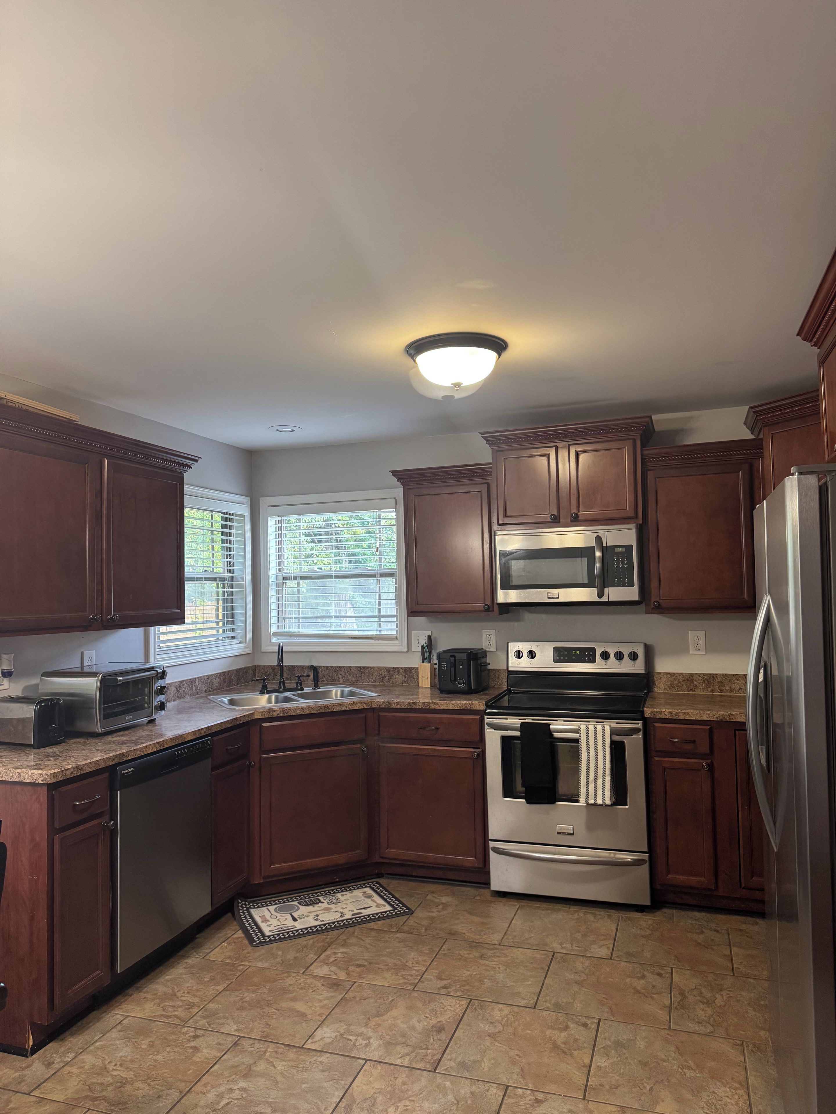 A kitchen with wooden cabinets, stainless steel appliances, a built-in microwave, and a granite countertop.