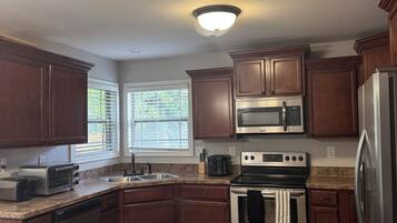 A kitchen with wooden cabinets, stainless steel appliances, a built-in microwave, and a granite countertop.
