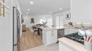 Une cuisine moderne avec des meubles blancs, un îlot central et une cuisinière à gaz.