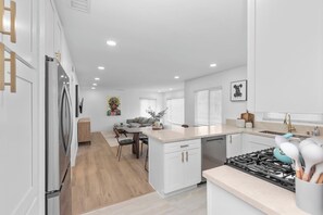Una cocina moderna con muebles blancos, una isla central y una estufa a gas.