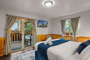 A bedroom with a bed, a view of the outdoors, and a sliding glass door. - Cozy modern cabin in Lower Moonridge, 5 minutes from Big Bear Mountain! (Big Bear Lake)