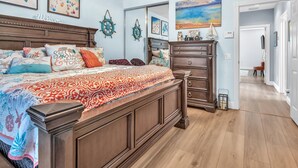 Ein Schlafzimmer mit einem großen Bett, einem Schminktisch, einem Spiegel und Bildern an den Wänden.