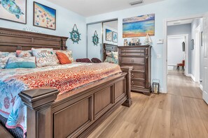A bedroom with a large bed, a dresser, a mirror, and artwork on the walls. - Snowbird Ready | Gated Pool Villa | Bonita (Bonita Springs)