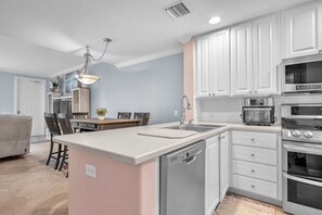 Eine moderne Küche mit weißen Schränken, einem eingebauten Geschirrspüler, einem Backofen mit separatem Umluftofen und einer Mikrowelle.