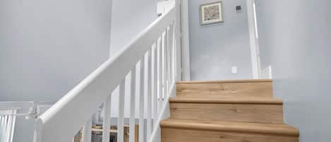 A wooden staircase with white railings leading to a landing.
