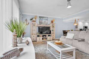 A living room with a TV, sofa, coffee table, and decorative items. - Bonita 3BR | Pool + Tennis | Monthly Min (Bonita Springs)